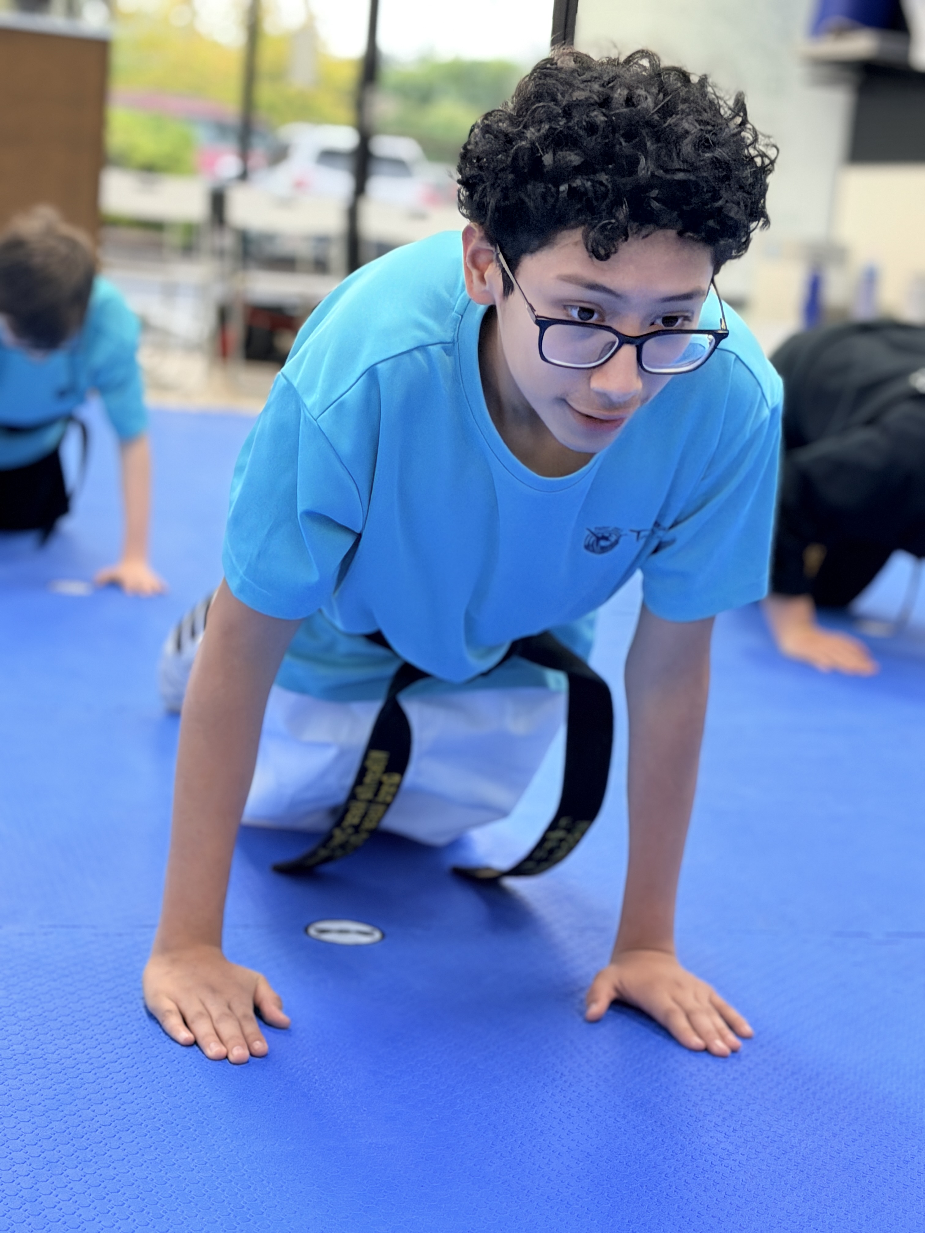 Black belt student with glasses doing push-ups during conditioning