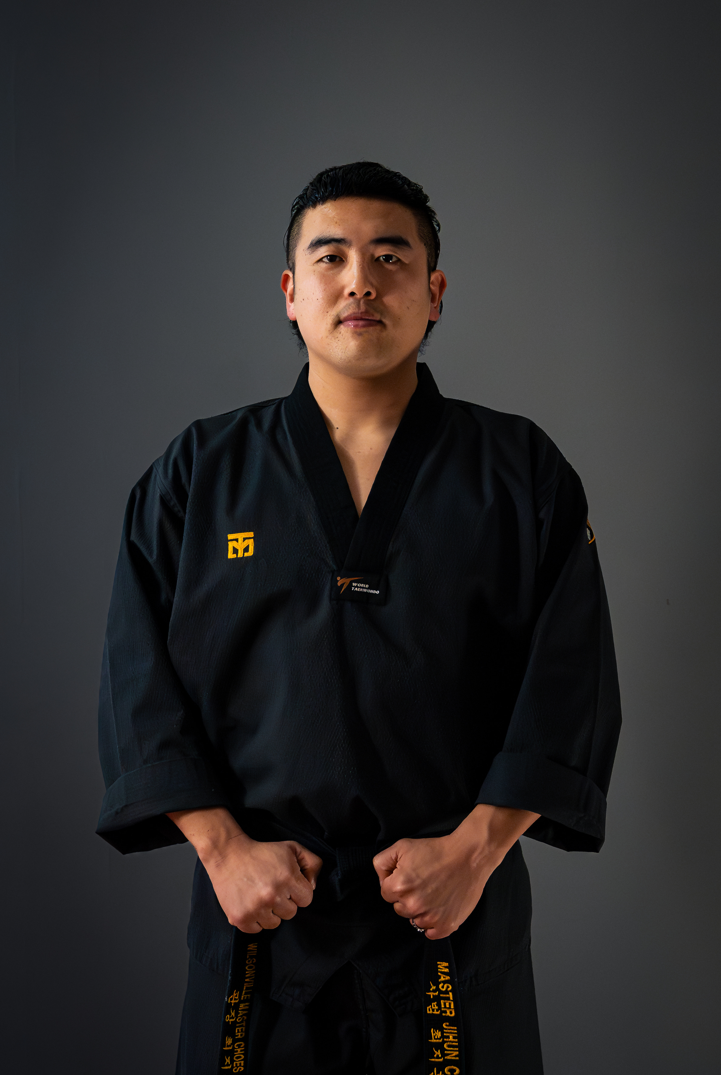 Master Jihun Choe in his black uniform, holding his embroidered black belt