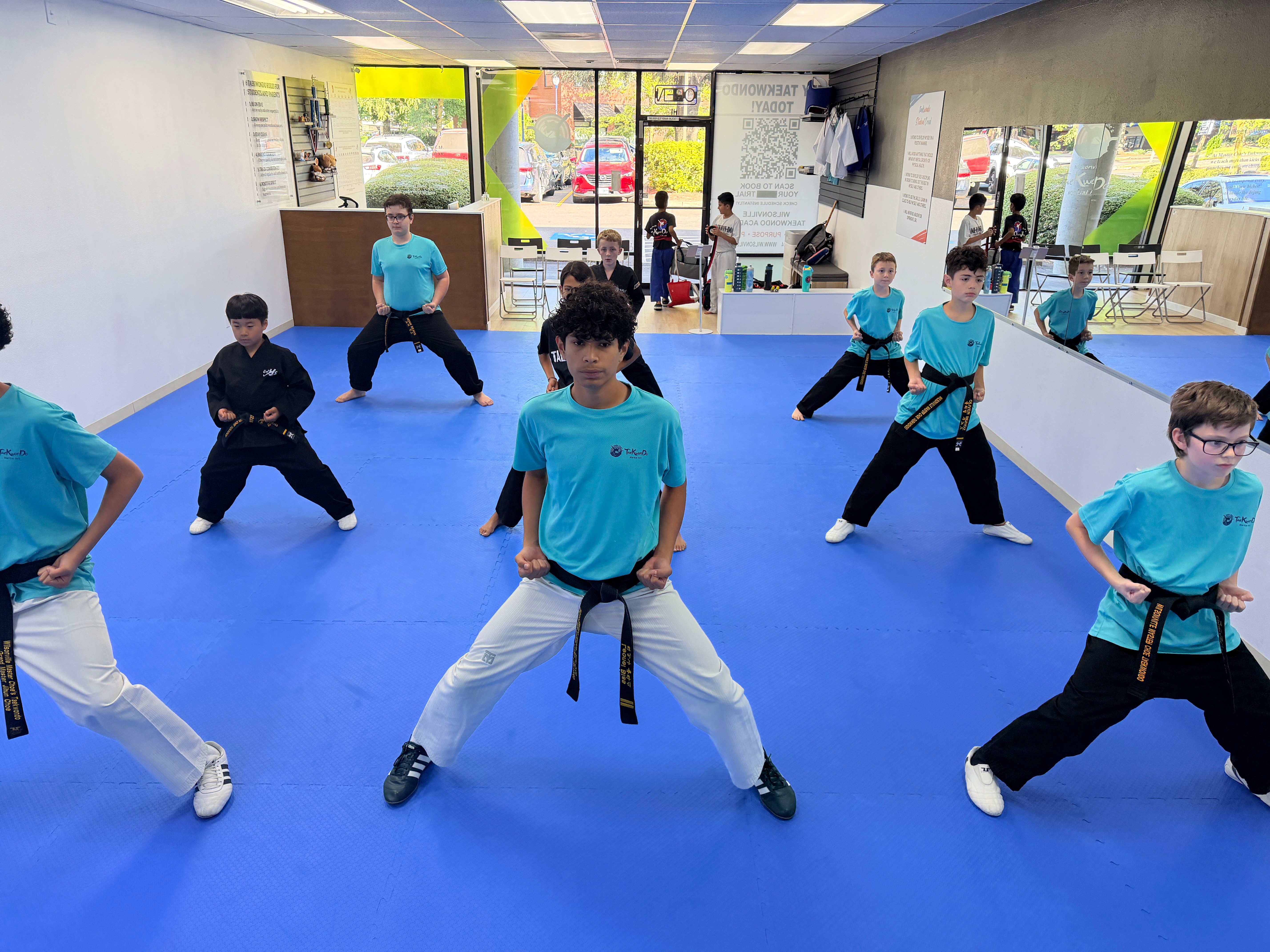 Black belt students holding a low stance together on the blue mat