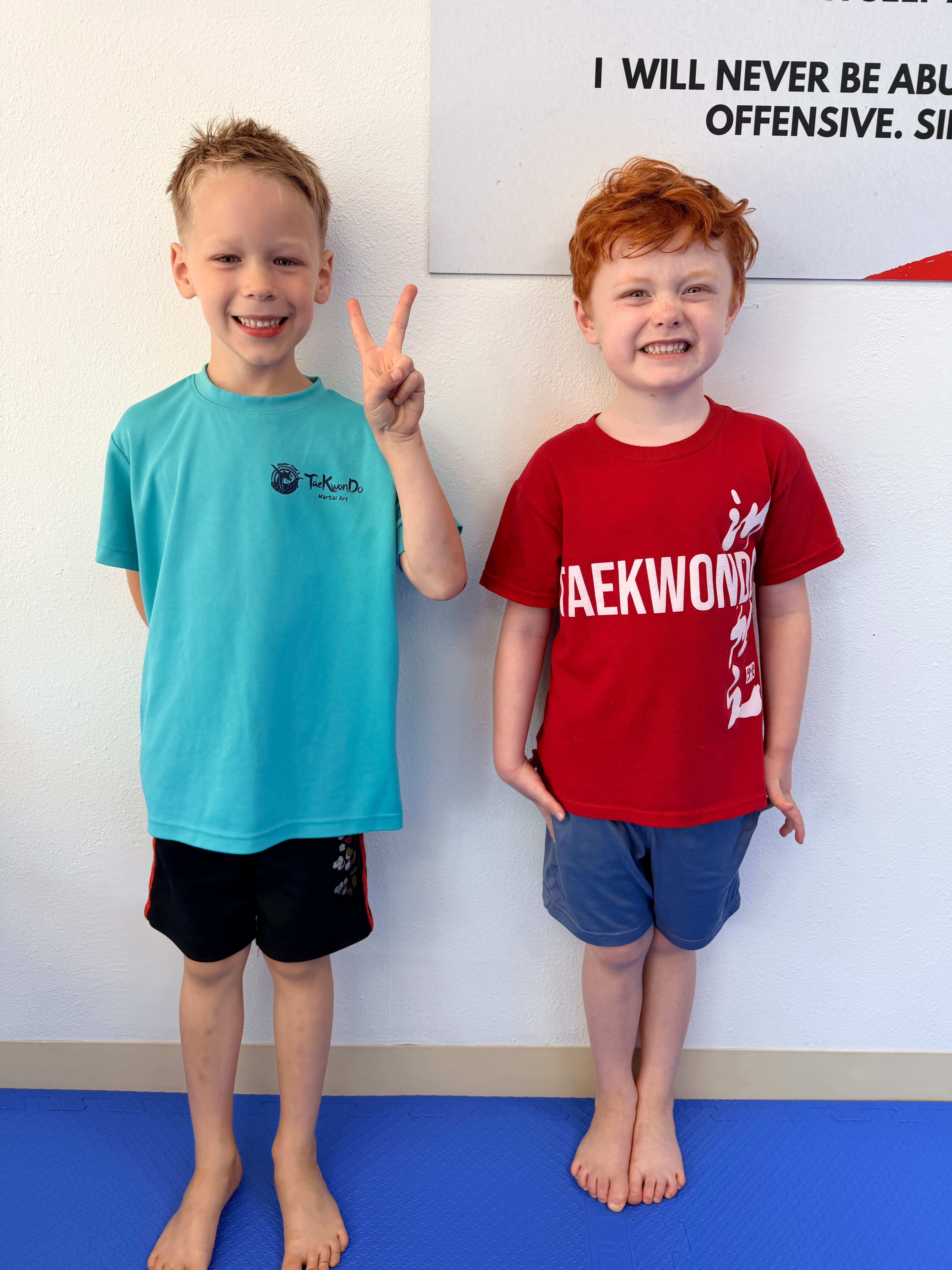 Two young students smiling, one making a peace sign